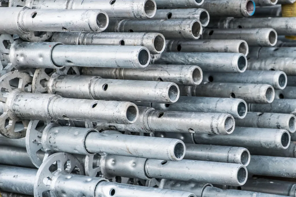 Stacked metal scaffolding pipes and components ready for rental use in Downey CA from Downey Scaffolding Rental